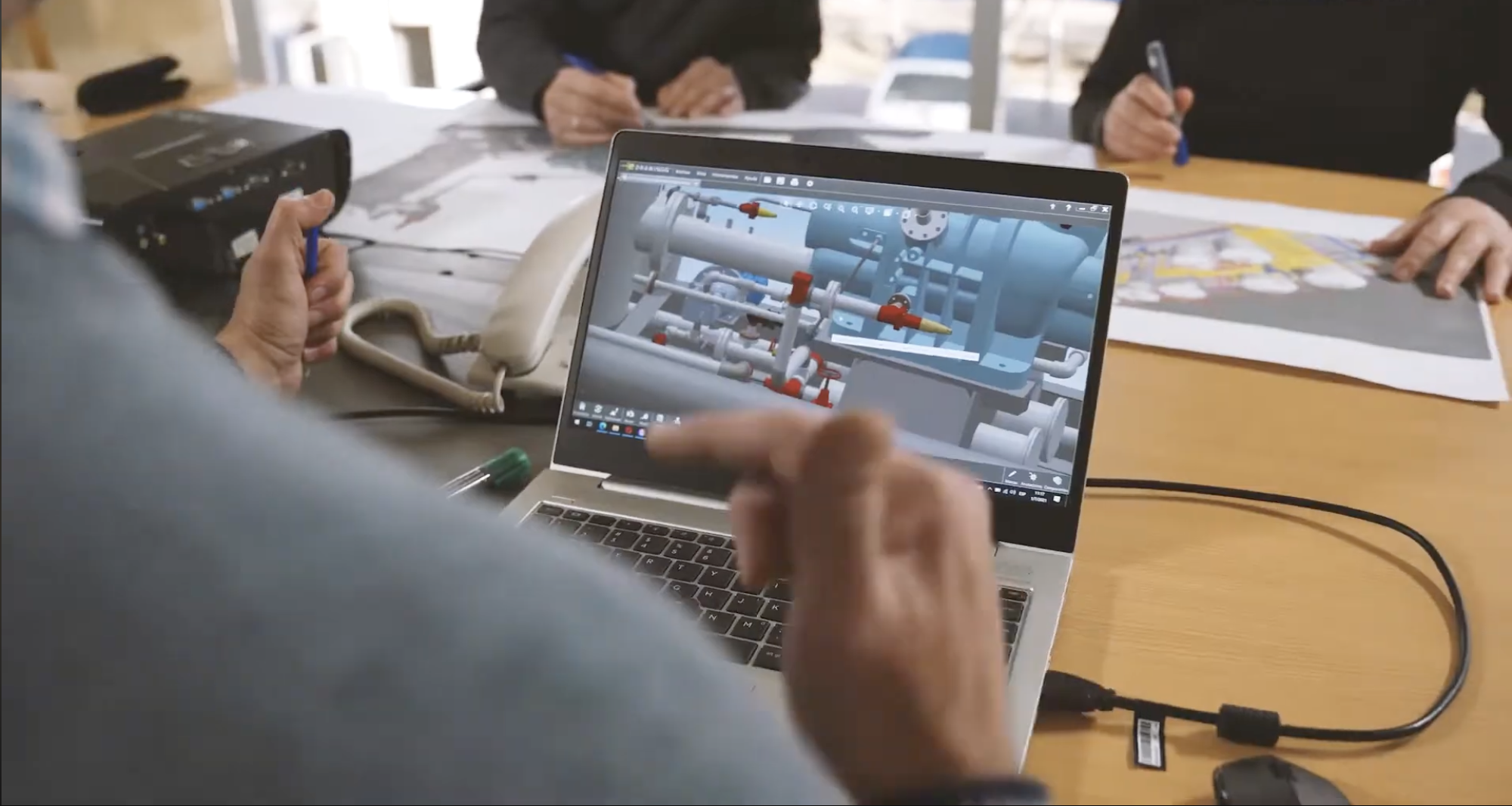 Ingenieros revisando el modelo 3D de una sala de máquinas en una notebook.